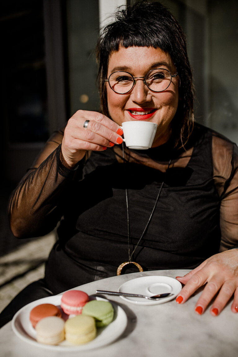 Frau mit rotem Lippenstift beim Kaffee trinken in Wangen. Von Unzufriedenheit keine Spur.
